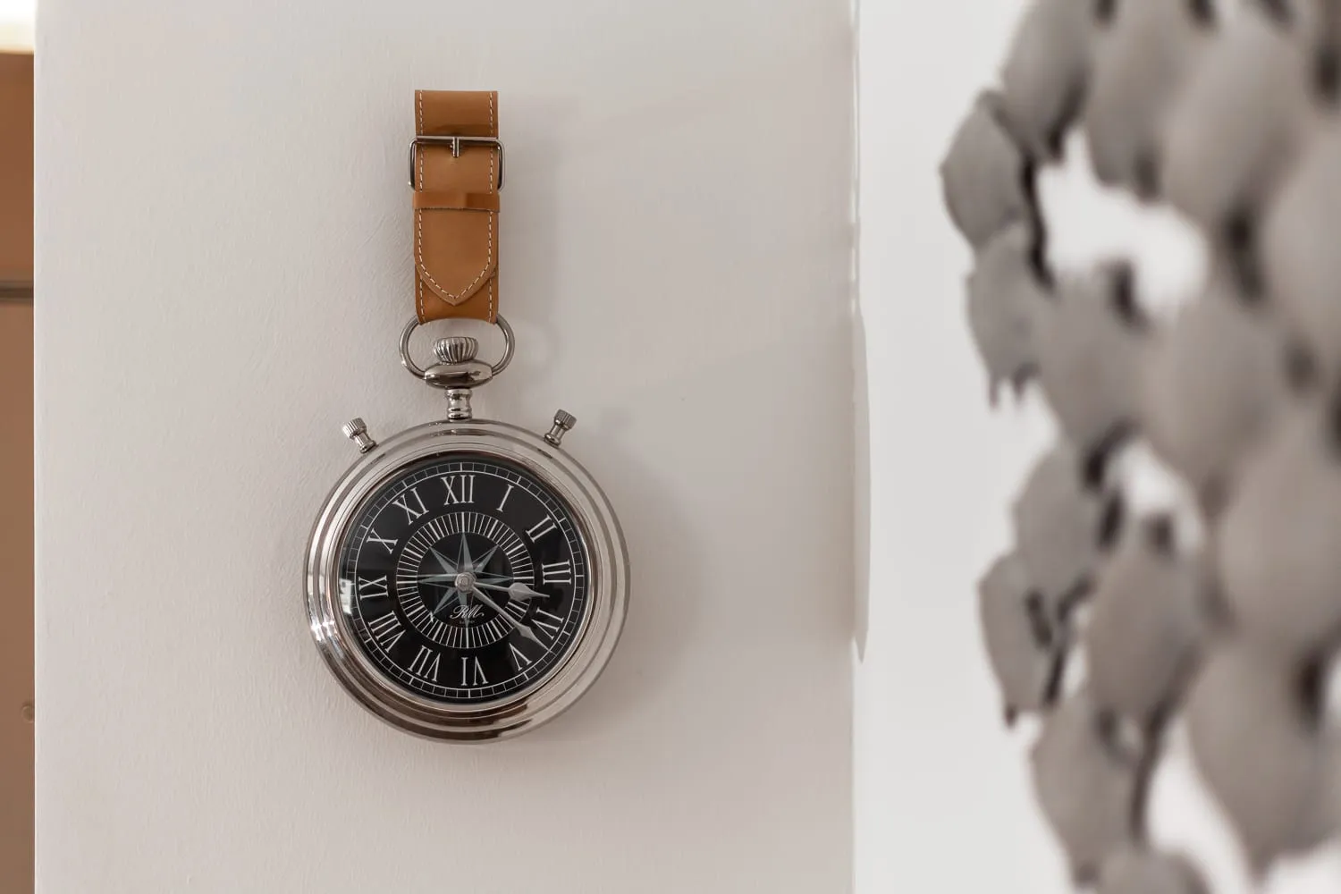 Eine Uhr mit Lederband an der weißen Wand