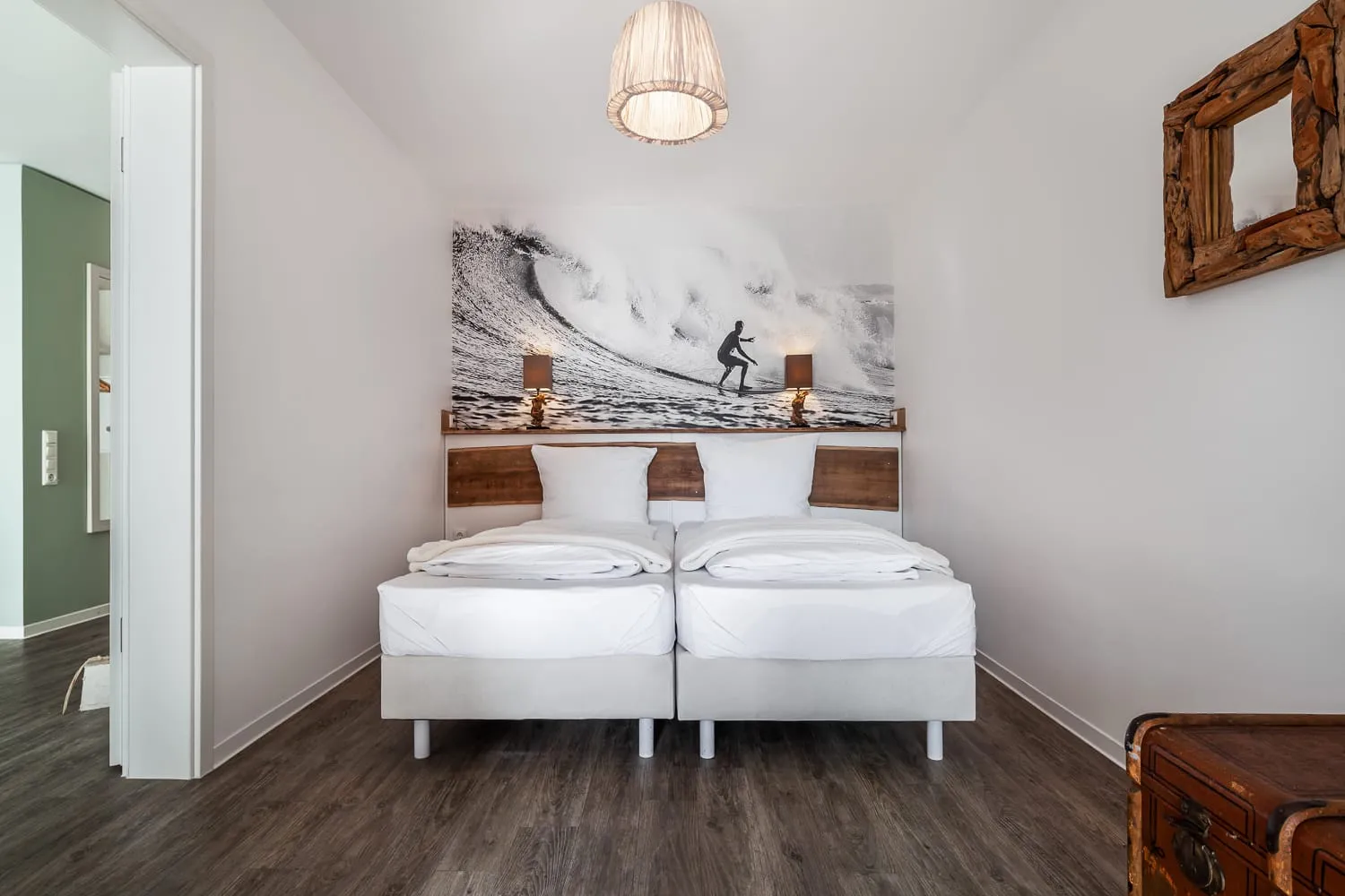 Das Schlafzimmer mit zusammengeschobenen Betten und einem Surferbild über dem Kopfteil