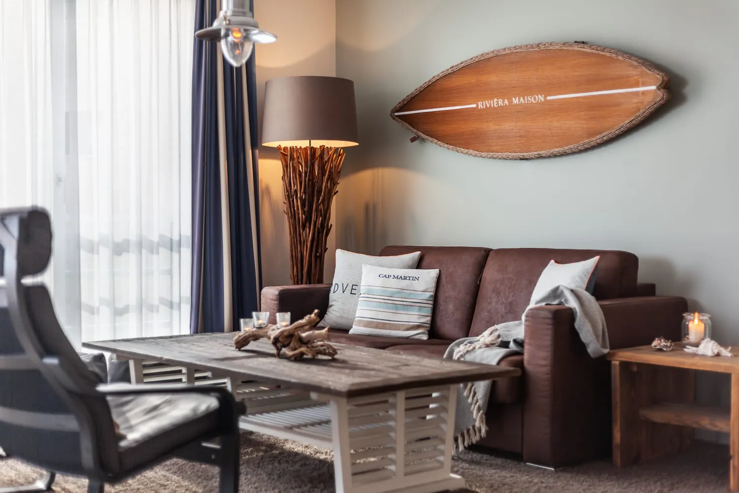 Das Sofa mit Kissen, Couchtisch aus Holz und eine Stehlampe aus Treibholz