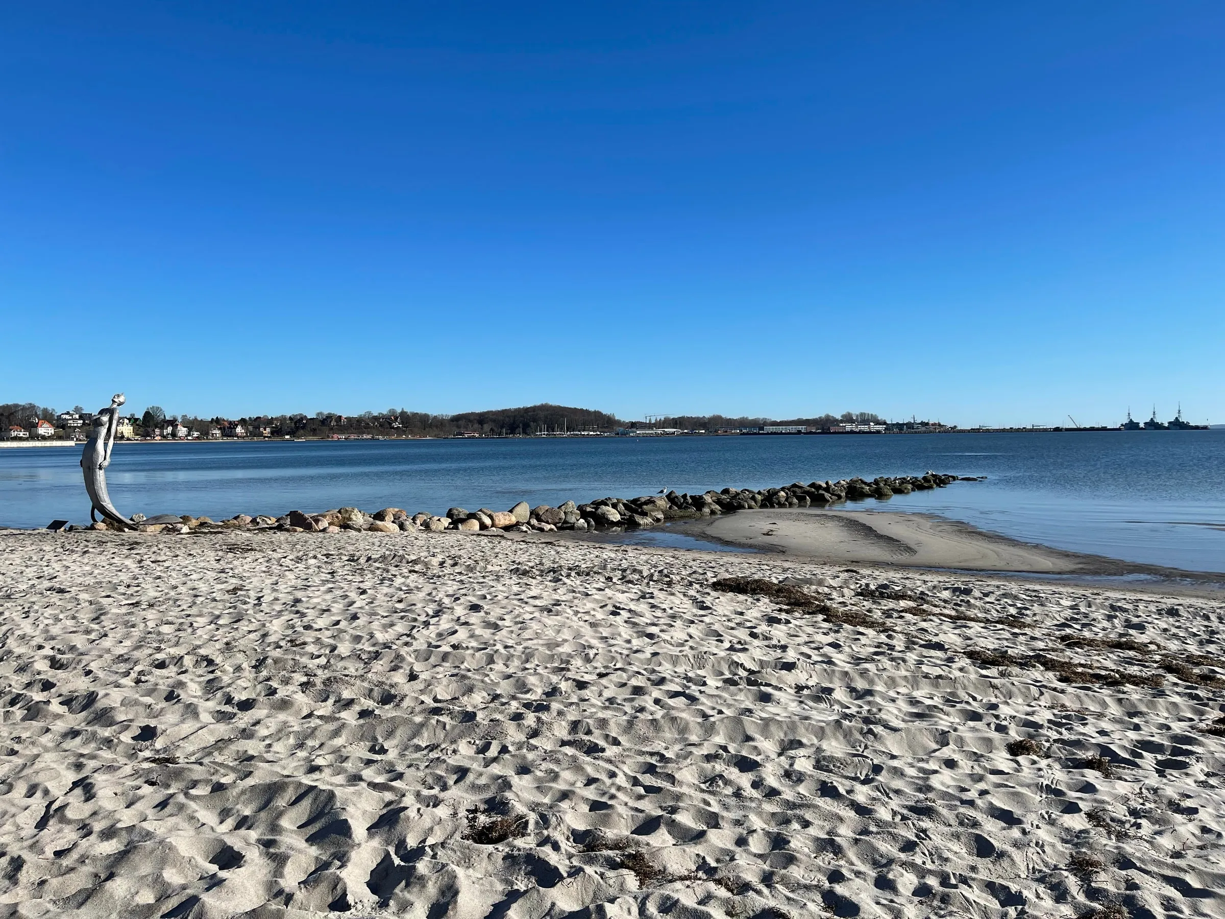 Der Sandstrand von Eckernförde an einem klaren Wintertag, im Hintergrund die Bucht
